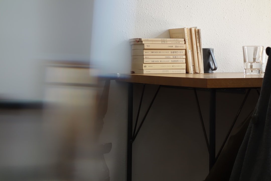 Stacked books and a glass on a simple wooden table.