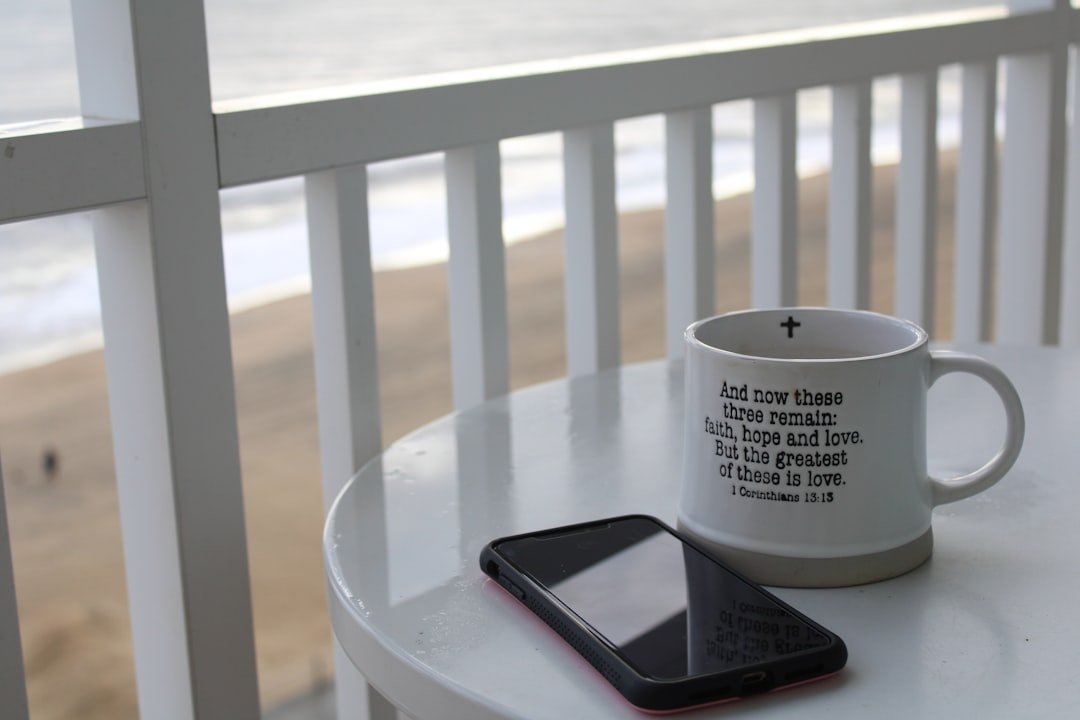 a cell phone sitting on top of a table next to a cup